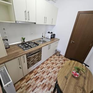 a kitchen with a table and a sink and a stove at Lovely apartment in Craiova +13 photos