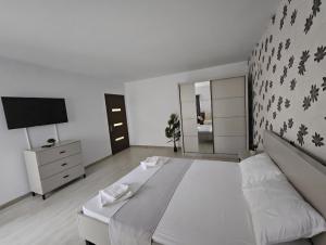 a white bedroom with a large bed and a television at Lovely apartment in Craiova