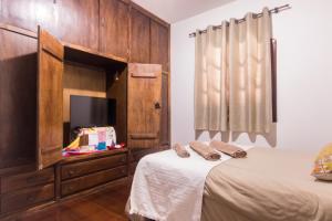 a bedroom with a bed and a dresser with a tv at Villa Bem Querer - Camomila in Mairiporã