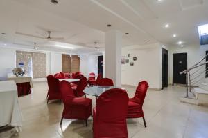 Un comedor con sillas rojas y una mesa en Collection O Cambridge, en Dhankot