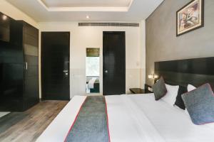 Un dormitorio grande con una cama blanca grande y armarios negros. en Collection O Cambridge, en Dhankot