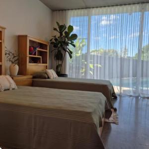 ein Schlafzimmer mit zwei Betten und einem großen Fenster in der Unterkunft Luxury Coastal Private Villa in Peregian Beach