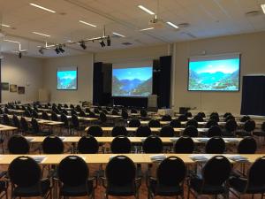 a large room with tables and chairs and screens at Thon PartnerHotel Jølster in Skei