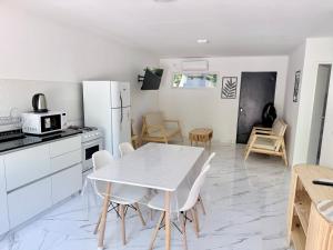 a white kitchen with a white table and chairs at Mar azul Loft in Mar Azul