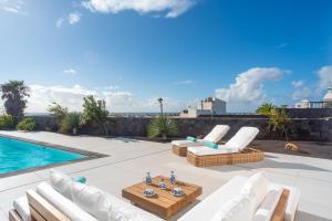 a patio with white chairs and a swimming pool at Ereza Hoopoe Villas in Playa Blanca