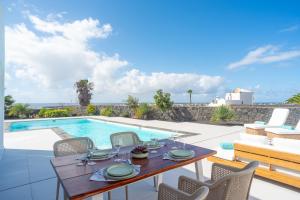 a patio with a table and chairs next to a swimming pool at Ereza Hoopoe Villas in Playa Blanca
