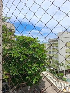 Hinter einem Maschendrahtzaun steht ein Baum. in der Unterkunft Apartamento Enseada in Guarujá
