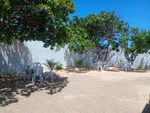 a row of chairs and trees in the sand at Hostel Mamitchesca in Canoa Quebrada