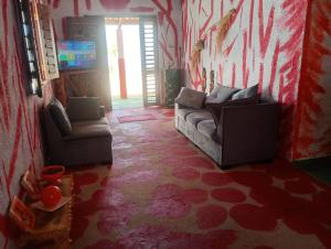 a living room with two couches and a tv at Hostel Mamitchesca in Canoa Quebrada