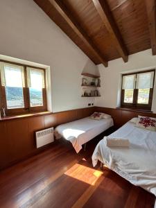 zwei Betten in einem Zimmer mit Fenstern und Holzboden in der Unterkunft Casa Riu in Riu de Cerdanya