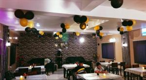 a restaurant with tables and balloons hanging from the ceiling at Hotel Sundaram in Deoghar