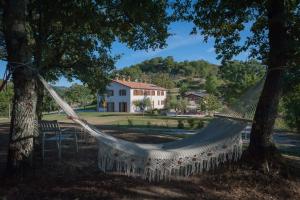 a hammock hanging between two trees in front of a house at Agriturismo Il Beccafico Alpaca in Mengara
