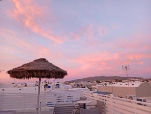 a patio with a straw umbrella and a table and chairs at The Best in Perissa +110 photos