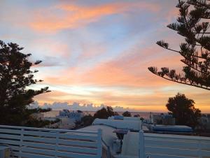 a sunset over a white fence in front of a building at The Best in Perissa