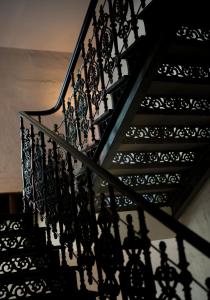 a staircase with black wrought iron railings and shadows at Bellhop Tbilisi in Tbilisi City