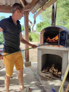 a man is using a stick to hit a fire in an oven at Les Bienfaits d'Harmonium in La Chapelle-Gaudin