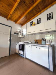 a kitchen with white cabinets and a stove at Casita funcional en Claromeco in Balneario Claromecó