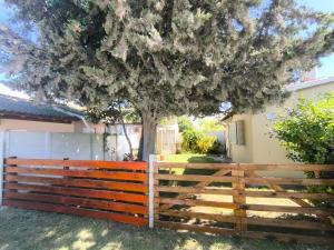 a wooden fence with a tree behind it at Casita funcional en Claromeco in Balneario Claromecó