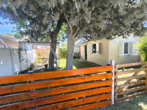 a wooden fence in front of a tree at Casita funcional en Claromeco in Balneario Claromecó +2 photos