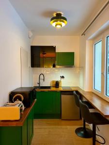 eine Küche mit grünen Schränken und einem Schreibtisch mit einem Stuhl in der Unterkunft Les Couleurs du Lac in Gérardmer