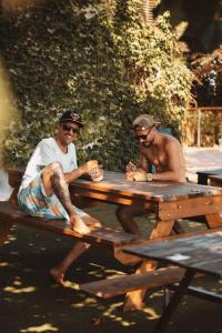 two men are sitting at a picnic table at Latas Surf House in Somo