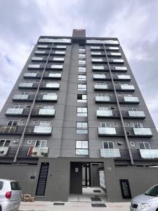 a tall building with cars parked in front of it at Loft Super aconchegante a 50mt da Vila Germânica com estacionamento gratuito in Blumenau
