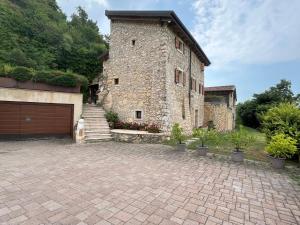 un grand bâtiment en pierre avec un garage et quelques plantes dans l'établissement Località busa, à Colognola ai Colli