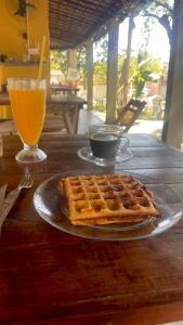 Un plato de gofres en una mesa de madera con una bebida. en El Gringo Banheiro Compartilhado, en Cabo de Santo Agostinho