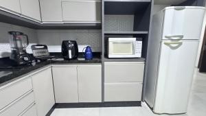 una cucina bianca con frigorifero e forno a microonde di Casa ampla próxima ao centro a Dourados