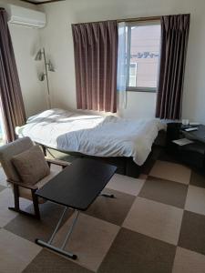 a bedroom with a bed and a chair and a table at れのん in Okazaki