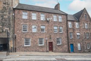 ein altes Backsteingebäude mit einer roten Tür in der Unterkunft Bow Apartment in Stirling