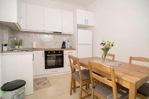 eine Küche mit weißen Schränken und einem Holztisch mit Stühlen in der Unterkunft Ioulia in Kalamata