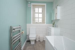 ein weißes Bad mit einem WC und einem Fenster in der Unterkunft Bow Apartment in Stirling