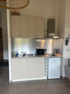 una cucina con mobili bianchi e un forno a microonde di Charmante petite maison provençale a Grasse Altre 11 foto