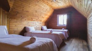 Una habitación con tres camas en una cabaña de madera. en Travels Hotel, en Osorno