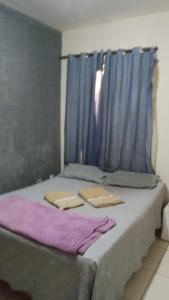 坎普斯戈伊塔卡济斯Apto Toulon的一张床，床边有一扇挂着蓝色窗帘的窗户