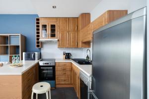 a kitchen with wooden cabinets and a stainless steel refrigerator at Obywatelska Comfort Apartment by BookingHost in Łódź