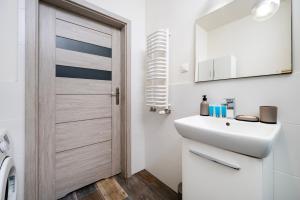 a bathroom with a white sink and a door at Obywatelska Comfort Apartment by BookingHost in Łódź +14 photos
