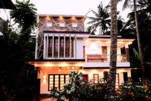 a house with a palm tree in front of it at Dean Dale Cottages in Thekkady