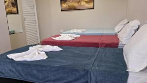 two beds with towels sitting on top of them at Suíte Harmonia 3 in Campo Grande