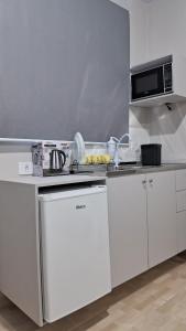 a white kitchen with a stove and a microwave at Suíte Harmonia 3 in Campo Grande
