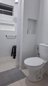 a white bathroom with a toilet and a shower at Suíte Harmonia 3 in Campo Grande