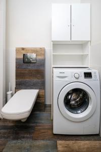 a bathroom with a washing machine and a toilet at Obywatelska Comfort Apartment by BookingHost in Łódź
