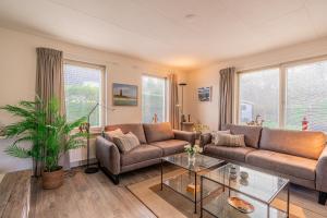 ein Wohnzimmer mit 2 Sofas und einem Glastisch in der Unterkunft Villapark Kamperfoelie 91 in De Koog