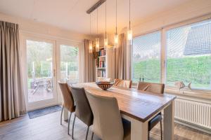 ein Esszimmer mit einem Holztisch und Stühlen in der Unterkunft Villapark Kamperfoelie 91 in De Koog