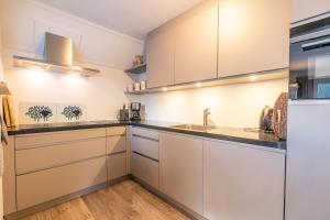 eine Küche mit weißen Schränken und einer Spüle in der Unterkunft Villapark Kamperfoelie 91 in De Koog