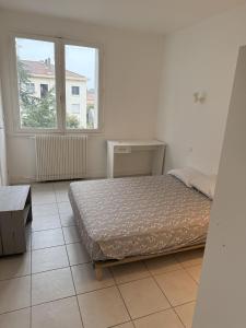 een slaapkamer met een bed en een groot raam bij Appartement 2 chambres parking draps et serviettes non fournies in Agen
