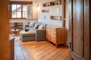 Una sala de estar con un sofá y suelo de madera. en MOOKI Country Apartment, en Villach