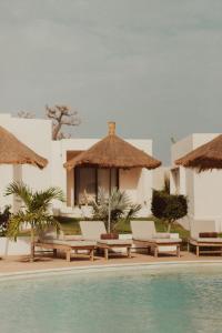 Un complejo con piscina y sillas y un edificio. en Kawga Hôtel, en Ngaring