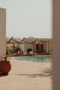 Una piscina con sombrillas y un resort. en Kawga Hôtel, en Ngaring
